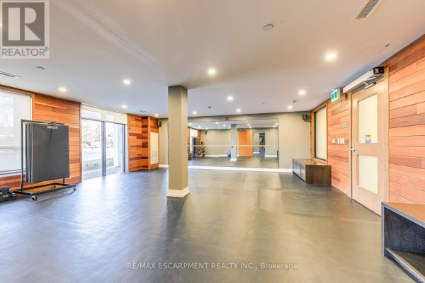 Fitness room with mirrors, wood walls, and exercise equipment - 303 - 320 Plains Road E Burlington