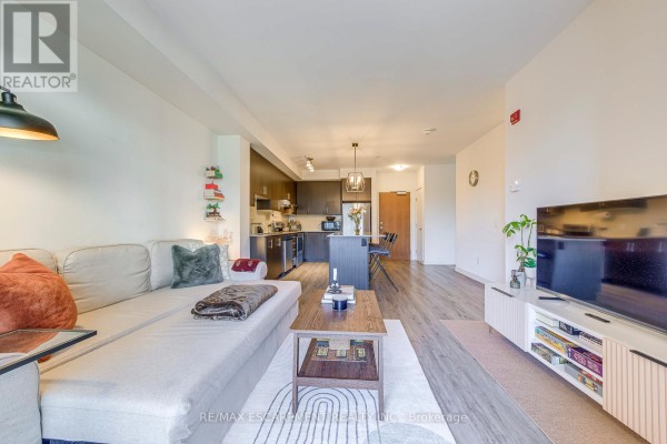 Living room with sectional sofa, kitchen island, and TV - 303 - 320 Plains Road E Burlington