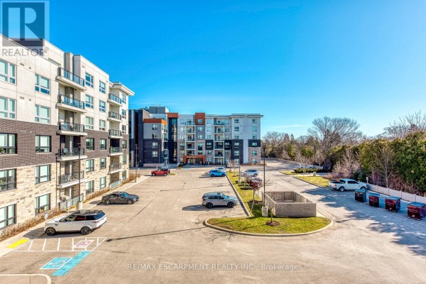 Modern apartment building with balconies and parking lot - 303 - 320 Plains Road E Burlington