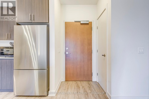 Hallway with stainless steel fridge and wood grain cabinets - 303 - 320 Plains Road E Burlington