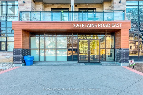 Modern building entrance with 320 Plains Road East signage - 303 - 320 Plains Road E Burlington