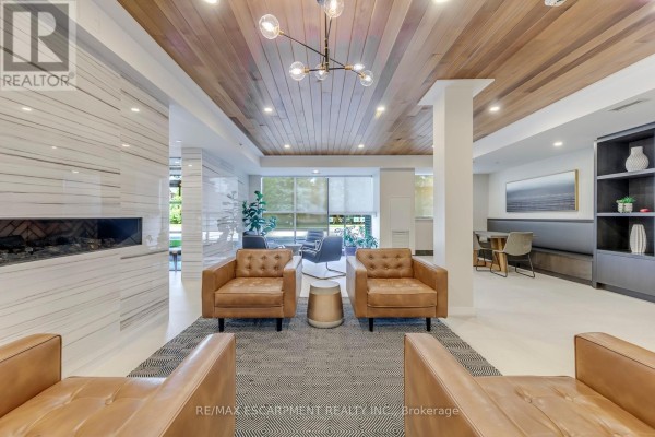 Building lobby with a reception desk, mailboxes, seating area, and wood-paneled ceiling. - 303 - 320 Plains Road E, Burlington