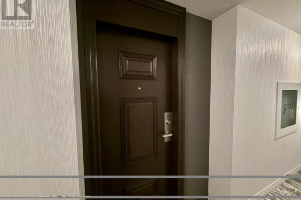 A dark brown apartment door with a silver handle on a textured hallway wall. - 303 - 39 Pemberton Avenue, Toronto