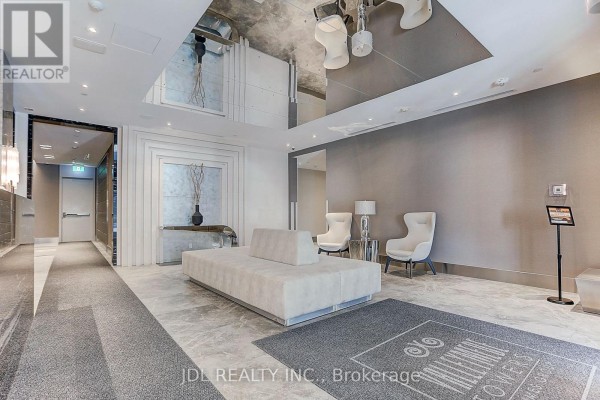 Modern lobby seating area with a long cream sofa and two white armchairs. - 303 - 398 Highway 7 Street E, Richmond Hill