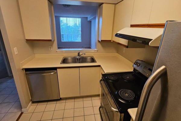 Kitchen with white cabinets, beige counters, double sink, dishwasher, stove, and window. - 303 - 480 Mclevin Avenue, Toronto