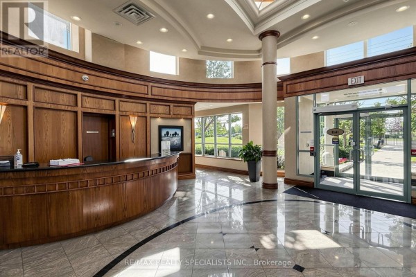 Building lobby with a polished marble floor, wood paneling, and a reception desk. - 303 - 4879 Kimbermount Avenue, Mississauga
