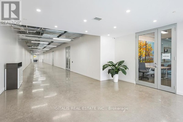 Modern office building hallway with polished concrete floors and glass doors. - 303 - 501 Alliance Avenue, Toronto