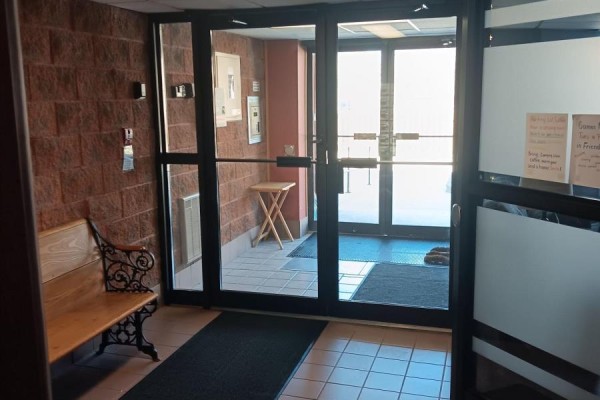 Interior view of the apartment building lobby with a bench, brick walls, and glass doors. - 303 - 536 11th Avenue, Hanover