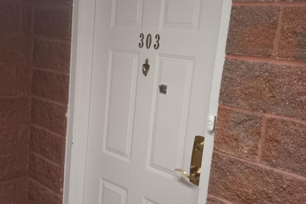 White apartment door labeled "303" with a gold handle, knocker, and doorbell. - 303 - 536 11th Avenue, Hanover