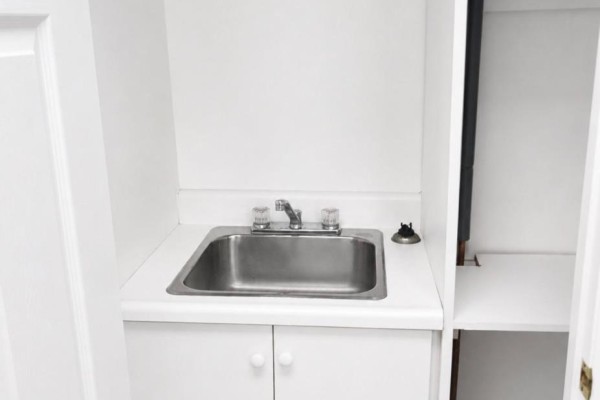 Empty room with light wood-look flooring, white walls, and multiple doors, with chairs lined up. - 303 - 66 Gerrard Street E, Toronto