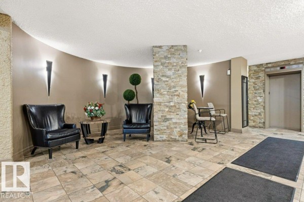 The entrance to a concrete apartment building with a covered walkway, stairs, and a ramp. - #303 10045 117 St Nw, Edmonton