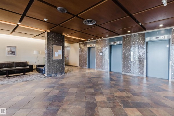Building lobby with elevators, tile flooring, a cork board, and a seating area. - #303 10883 Saskatchewan Dr Nw, Edmonton