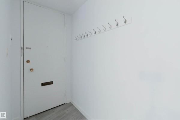 White apartment entrance door with a silver handle and a coat rack on the white wall. - #303 10883 Saskatchewan Dr Nw, Edmonton