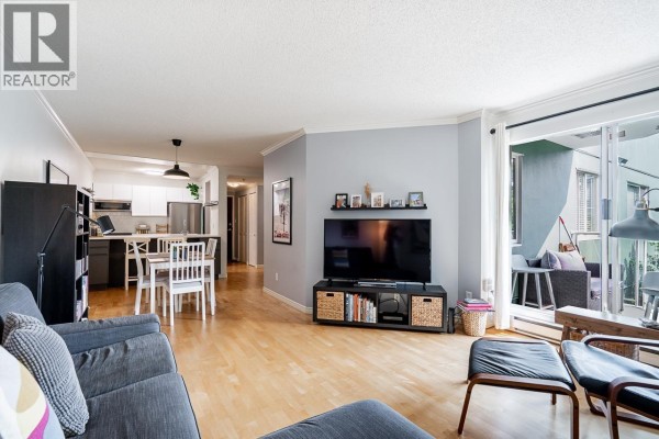 Living room showing sofa, media console, and patio doors leading to an outdoor seating area. - 303 1510 W 1st Avenue, Vancouver