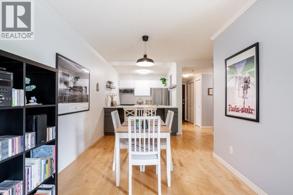 Dining area with a white table and chairs, overlooking the kitchen and a hallway. - 303 1510 W 1st Avenue, Vancouver