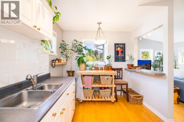 Dining area and entryway with a large mirror, wooden table, and a white front door. - 303 1528 Bowser Avenue, North Vancouver