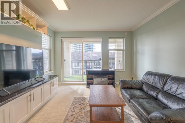 Cozy living area with large windows, coffee table, and access to outdoor space. - 303 4799 Brentwood Drive, Burnaby