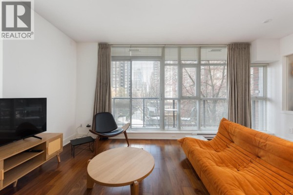 Living room with large windows, orange sofa, and modern furniture. - 303 988 Richards Street, Vancouver