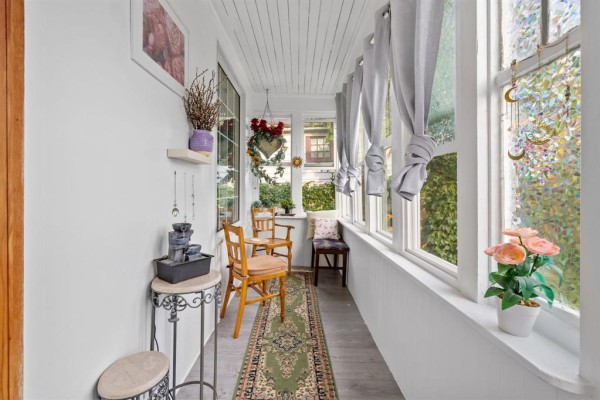 Interior of a sunroom with wooden chairs, a patterned rug, and white walls. - 303 Chalmers Avenue, Winnipeg