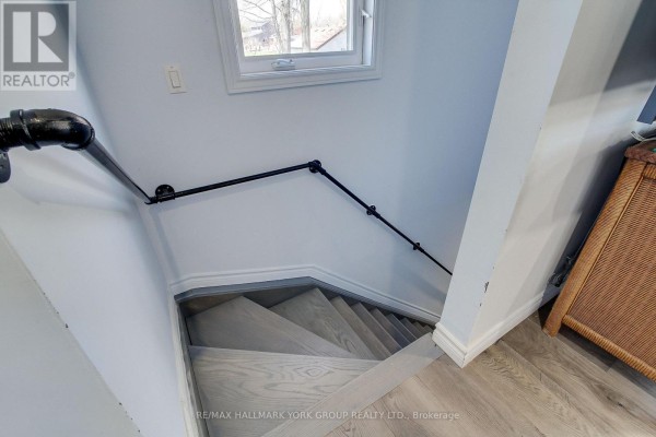 Wooden staircase with black metal pipe railings leading down into a room. - 303 Lake Dr East Apt A Drive, Georgina