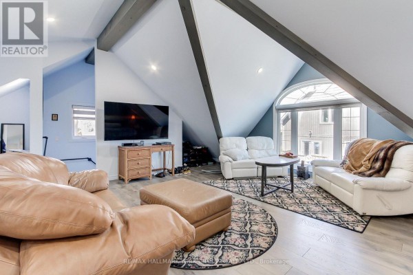 Living area with tan and white sofas, coffee table, ottoman, and television. - 303 Lake Dr East Apt A Drive, Georgina