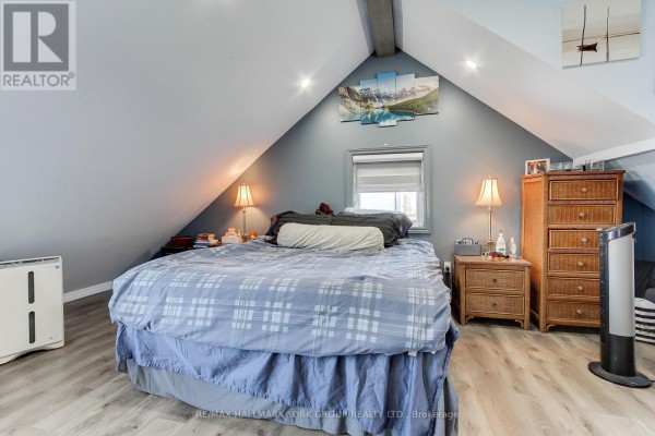Bedroom with a king-size bed, nightstands, dresser, and vaulted ceilings. - 303 Lake Dr East Apt A Drive, Georgina