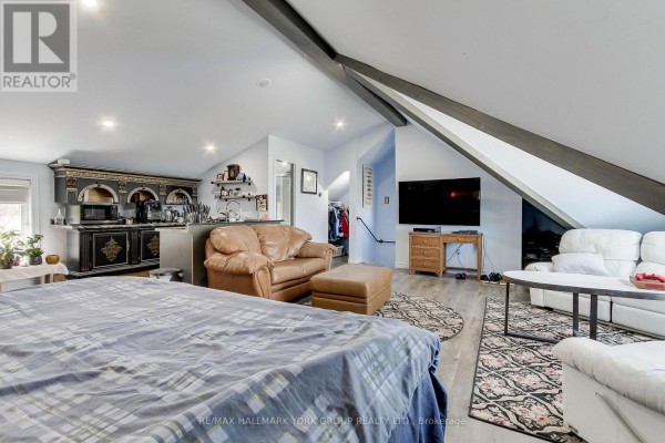 Open concept living space with a bed, sofas, television, and kitchenette area. - 303 Lake Dr East Apt A Drive, Georgina