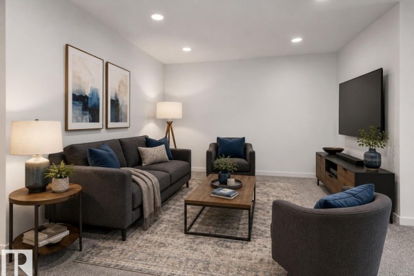 Living room with dark grey sofa, blue armchair, coffee table, and electric fireplace beside a large window with field view. - 303 Linden Lo, Leduc