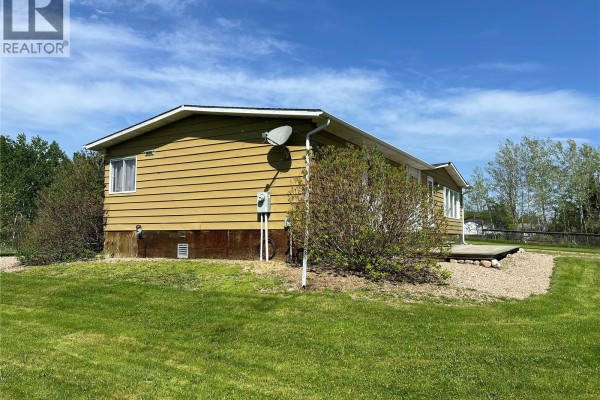 Exterior of a mustard-yellow mobile home with siding, windows, and surrounding green lawn. - 303 Main Street, Green Lake