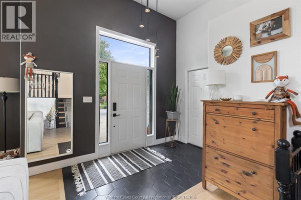 Foyer with dark grey walls, white front door, a wooden shoe cabinet, and a hexagonal tile floor. - 303 Stone Ridge Avenue, Amherstburg