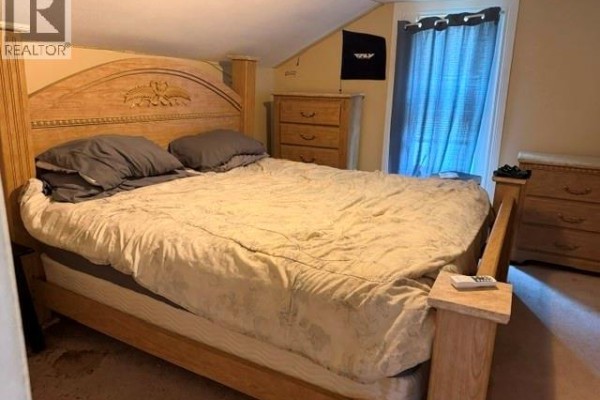 Bedroom with large wooden bed, dresser, and window - 303 Wellington Street West Chatham