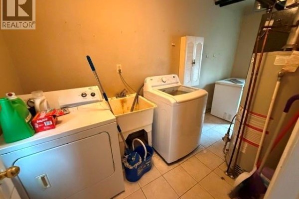Laundry room with washer, dryer, sink, and water heater - 303 Wellington Street West Chatham