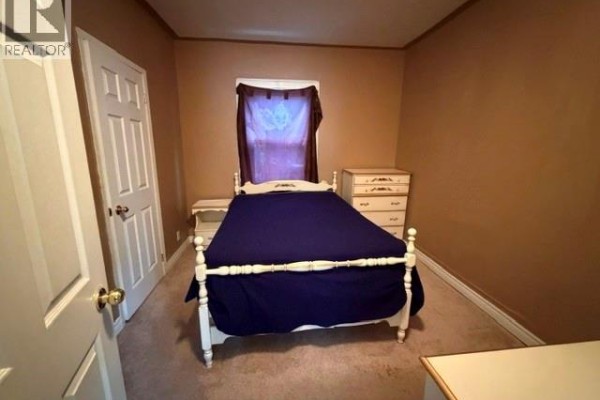 Bedroom with white bed frame, dresser, and door - 303 Wellington Street West Chatham