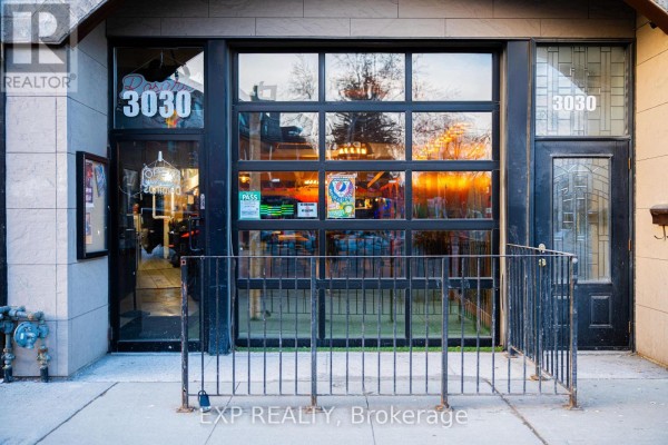 Close-up of entrance with glass doors and railing, showcasing interior visibility - 3030 Dundas Street W, Toronto