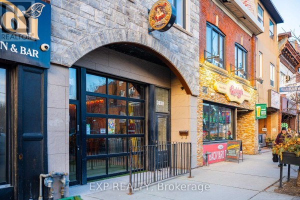 Side view of '3030' entrance with adjacent businesses and architectural details - 3030 Dundas Street W, Toronto