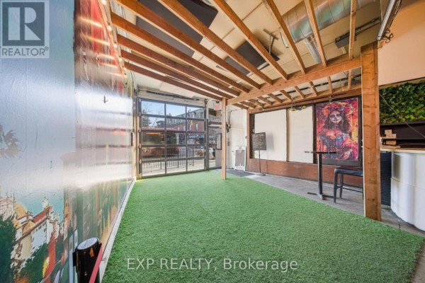 Interior space with artificial grass flooring, exposed beams, and large windows - 3030 Dundas Street W, Toronto