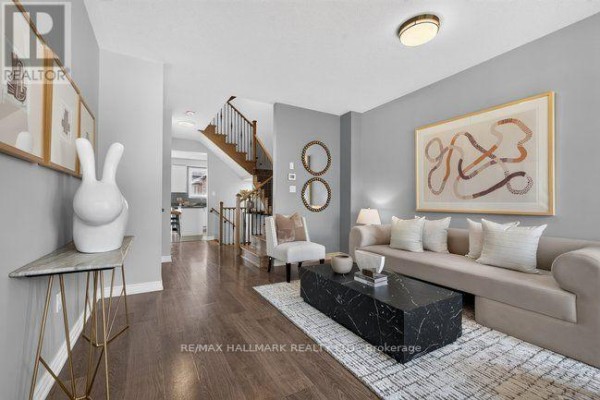 Living room with gray walls, hardwood floors, a beige sofa, and a black marble coffee table. - 3034 Eighth Line, Oakville