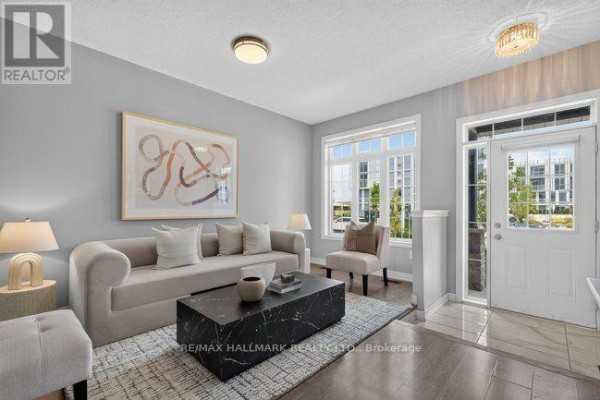 Living room with gray walls, hardwood floors, a beige sofa, and a view of the front entrance. - 3034 Eighth Line, Oakville