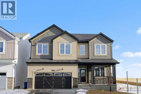 Side view of the beige house showing the rear entrance and small windows. - 3034 Southwinds Place Sw, Airdrie