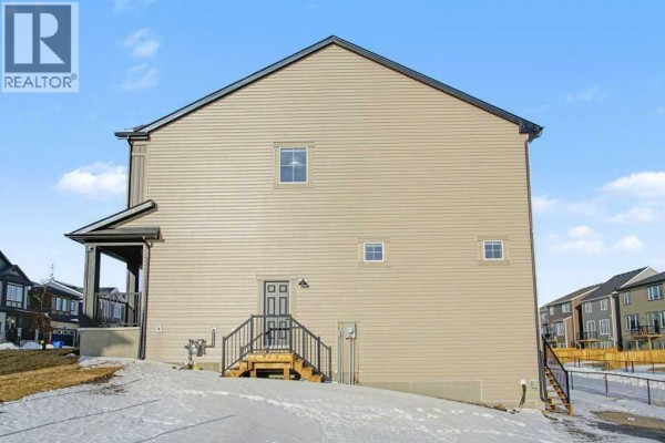 View of the rear of the beige house from the side, with snow on the ground. - 3034 Southwinds Place Sw, Airdrie