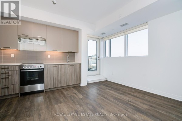 Apartment kitchen with light wood cabinets, stainless steel appliances, and dark wood laminate flooring. - 304 - 2301 Danforth Avenue, Toronto