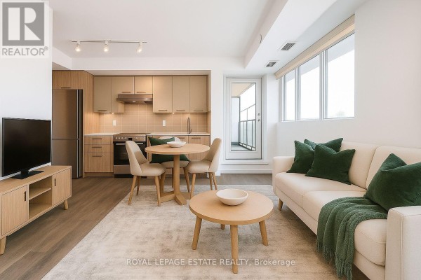 Living and dining area with a sofa, coffee table, dining table, chairs, and a TV stand. - 304 - 2301 Danforth Avenue, Toronto