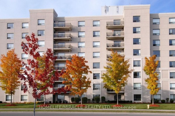 Exterior of a beige apartment building with balconies and trees showing fall colors. - 304 - 237 Auburn Drive, Waterloo