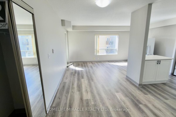 Open-concept living area with light grey floors, white walls, and large windows. - 304 - 237 Auburn Drive, Waterloo
