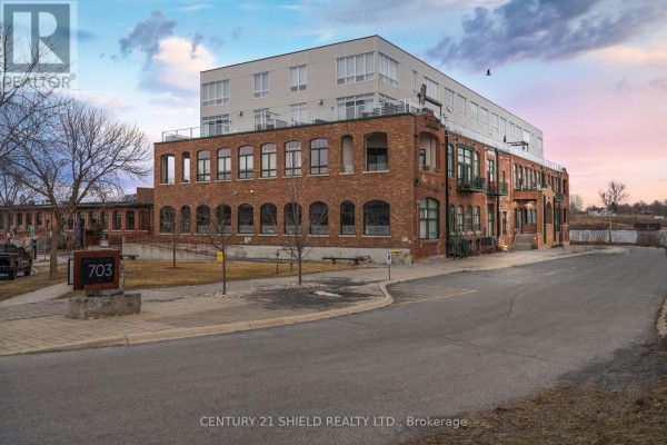 Exterior of a historic brick building with a modern addition, featuring arched windows and a street sign. - 304 - 703 Cotton Mill Street, Cornwall