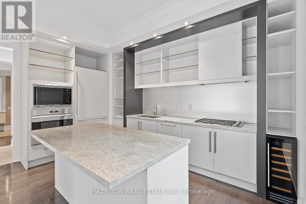 Modern kitchen with white cabinets, granite island, stainless steel appliances, and wine fridge. - 304 - 80 Yorkville Avenue, Toronto