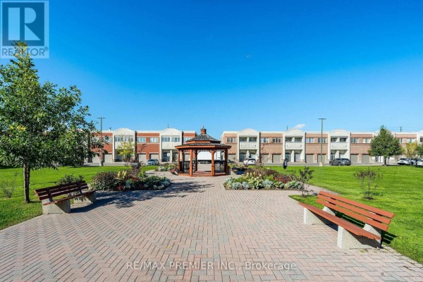 Outdoor common area with a brick patio, wooden gazebo, benches, and landscaping with apartment buildings in the background. - 304 - 9451 Jane Street, Vaughan