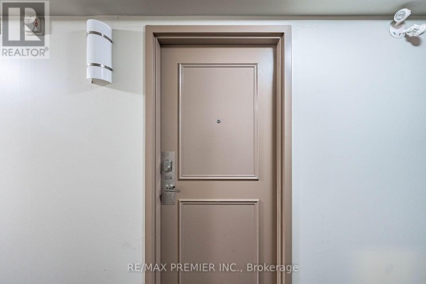 A closed beige apartment door with the number 304, a silver knob, and wall-mounted lighting fixtures. - 304 - 9451 Jane Street, Vaughan