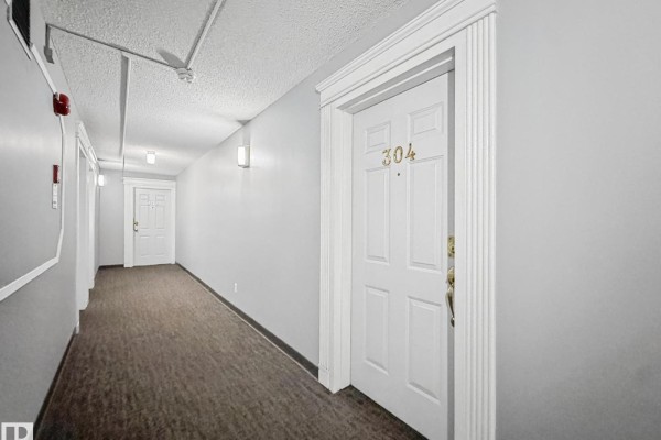 Exterior of a three-story brick and white siding apartment building with balconies and a parking lot. - #304 10320 113 St Nw, Edmonton
