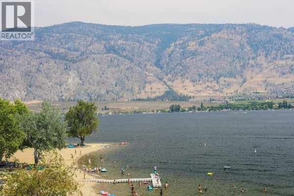 Aerial view of beach area with trees and mountains in the background. - 304-15 Park Place, Osoyoos